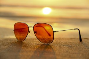 Gafas de sol sobre la arena representando el cansancio emocional y el diálogo interno femenino durante el verano.
