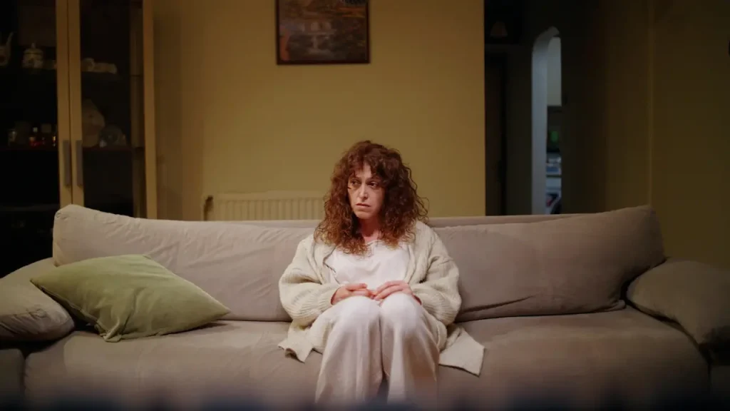 mujer de más de 45 años cansada sentada en el sofá sintiendo culpa al descansar.