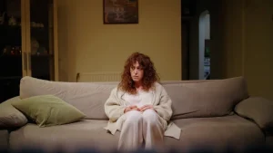 mujer de más de 45 años cansada sentada en el sofá sintiendo culpa al descansar.